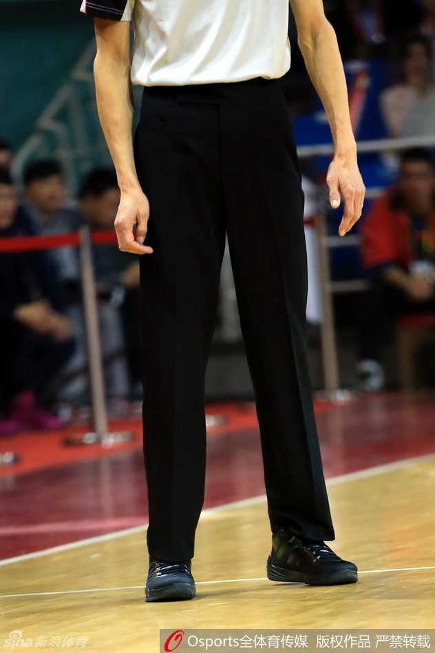 裁判在底线附近奔跑执法，双脚离地瞬间，球鞋的飞人标志与裁判严肃的面部表情形成鲜明对比
