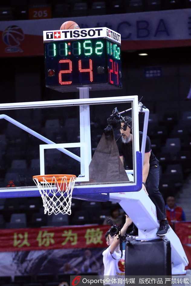 计时器上的孤独篮球与丁彦雨航的巧妙插曲 一名勇敢的工作人员爬上高高的篮球架,正伸出手臂去取卡在计时器上的篮球