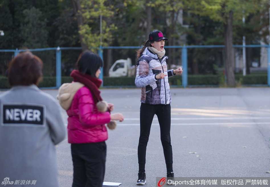 许诺老师微笑着为学生讲解运球技巧，尽管身高接近两米，她却弯下腰细心地纠正每一个动作，阳光下的笑容格外温暖。