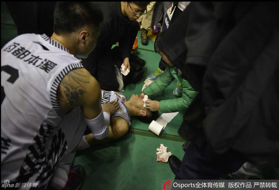 队医蹲在地上紧急为郭艾伦处理伤口，郭艾伦表情痛苦，眼眶周围已经肿胀，白色球衣上沾染了点点血迹。