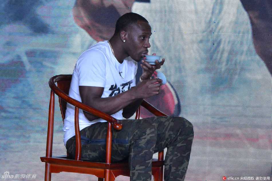 哈德森微微弯腰，专注地为小球员示范运球动作，篮球在他手中仿佛有了生命，旁边的小徒弟们聚精会神地模仿着每一个细节。