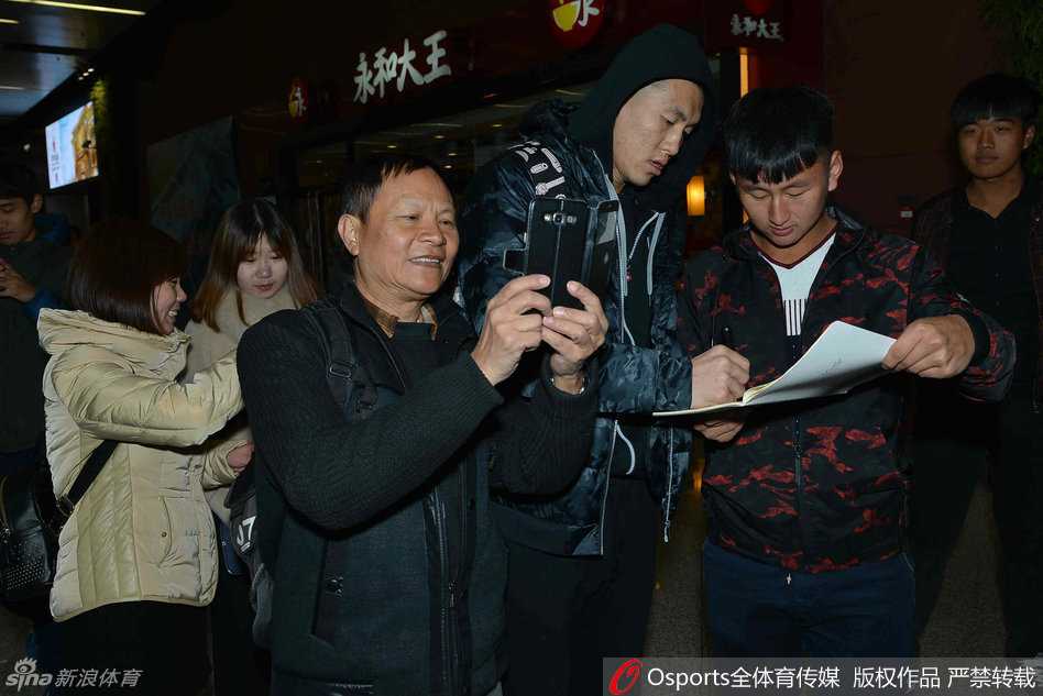 郭艾伦亲昵地搂着两位球迷的肩膀，对着镜头露出阳光般灿烂的笑容，仿佛邻家大哥哥