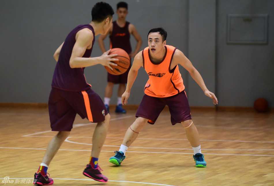 后卫金明在防守训练中如同猎豹般低姿滑步，他的双眼紧紧盯着对手的每一个细微动作，额头的汗水在灯光下闪烁，将全神贯注四个字诠释得淋漓尽致。