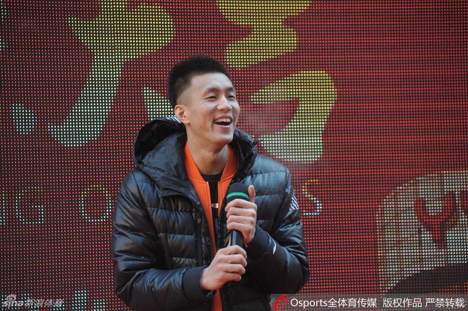 郭艾伦弯下腰，脸上挂着标志性的腼腆笑容，正专注地为面前的小球迷在篮球上签名，小球迷的眼神中充满了崇拜与期待。