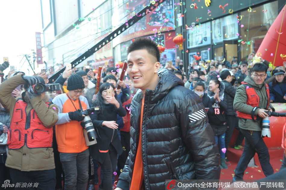 郭艾伦被粉丝团团围住，他伸出手与栏杆外的球迷击掌互动，脸上洋溢着开心的笑容，仿佛此刻他不是球星，而是与朋友们相聚的普通人。