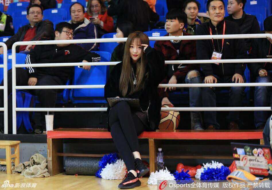 在比赛间隙，这位女球迷举手投足间流露出优雅气质，她轻轻梳理着自己的长发，眼神依然没有离开球场的方向，尽显东方女性的温婉韵味。