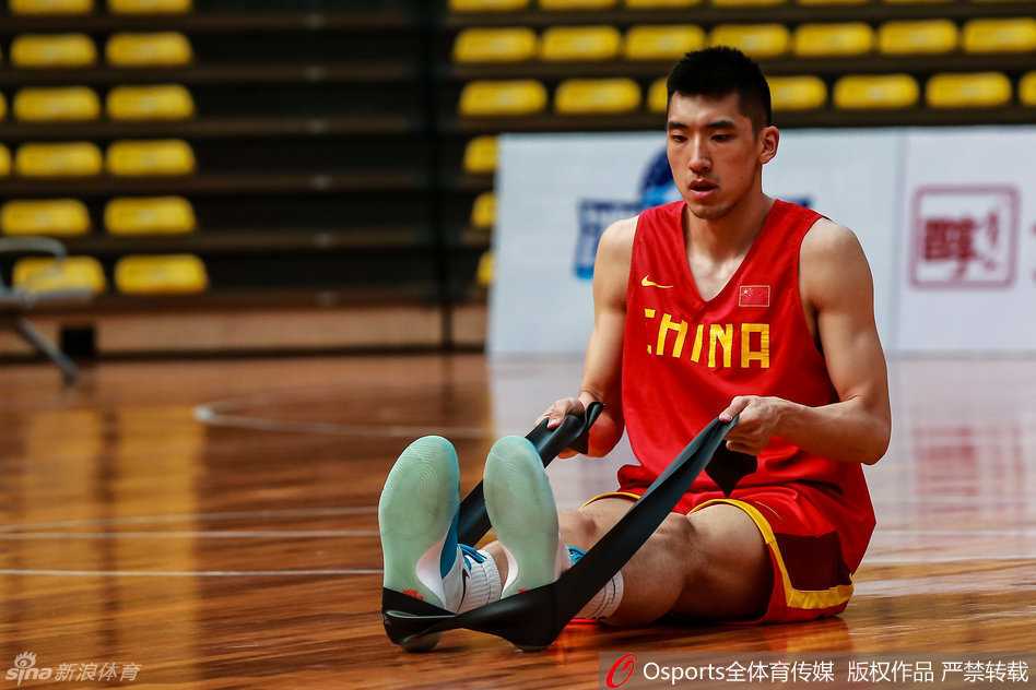 陶汉林独自在场边拉伸放松腿部肌肉，表情严肃而专注，汗水浸湿了球衣，显然在训练中非常投入。