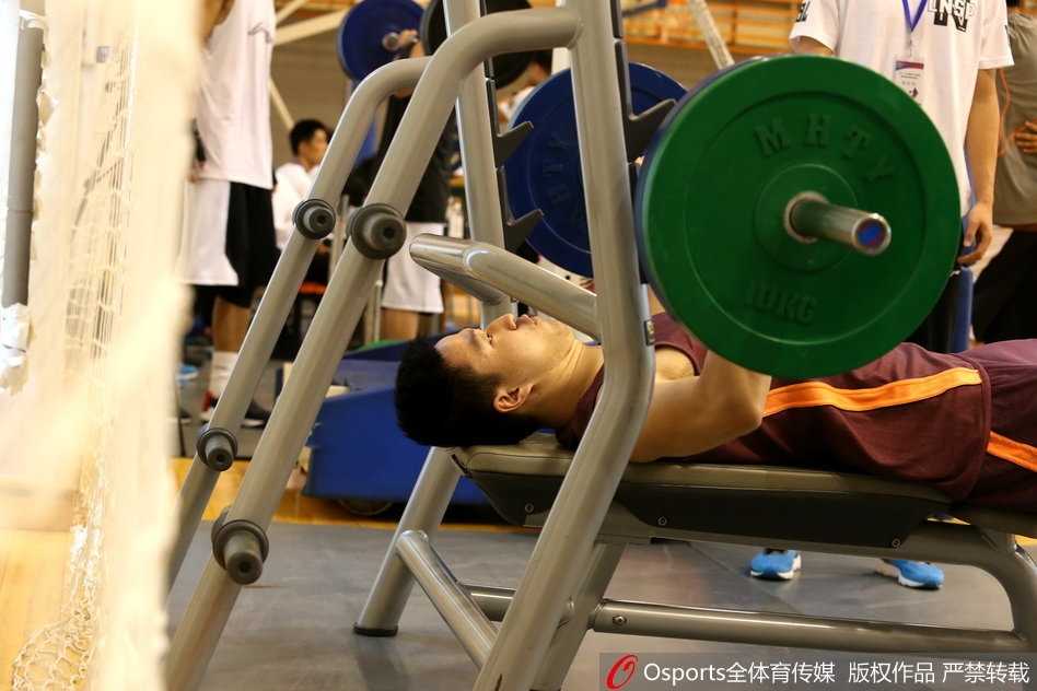 测试结束后，一名球员坐在地上放松肌肉，脸上露出如释重负的表情，身边的队友正在帮他记录成绩。