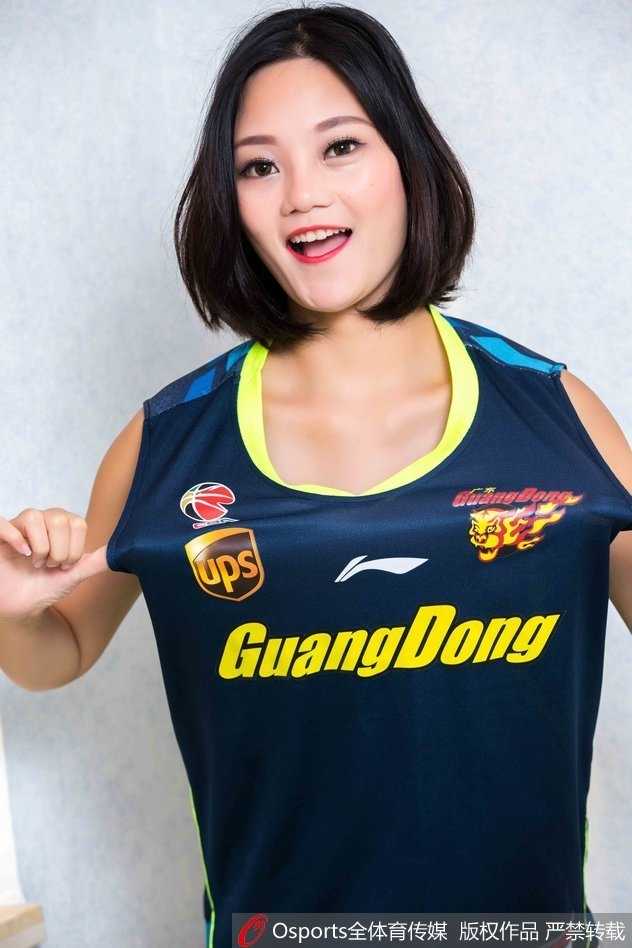 篮球宝贝双手叉腰，自信地望向远方，紧身的球衣短裤显得活力十足，背景虚化的看台衬托出她的青春气息。