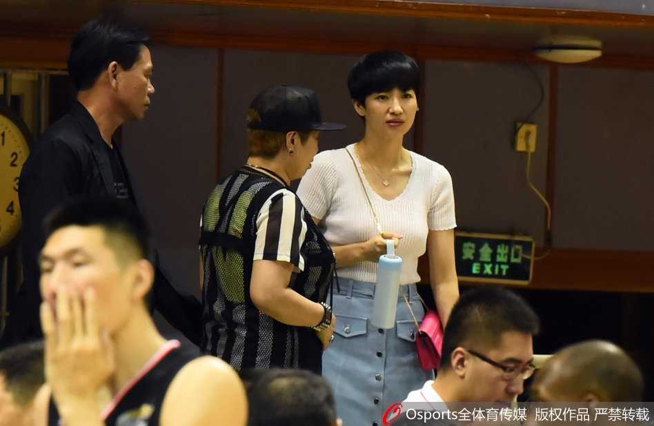 伍伯兰在赛场边露出温柔笑容，标志性的短发和精致的五官让她在人群中格外引人注目。