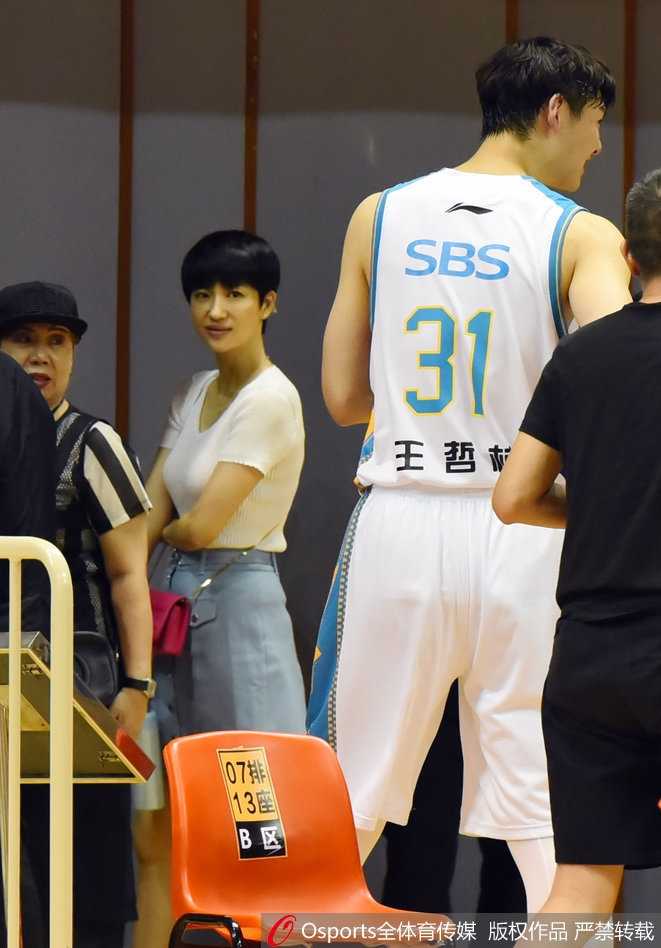 伍伯兰静坐场边，神情淡然，展现出一种运筹帷幄的女强人气质。