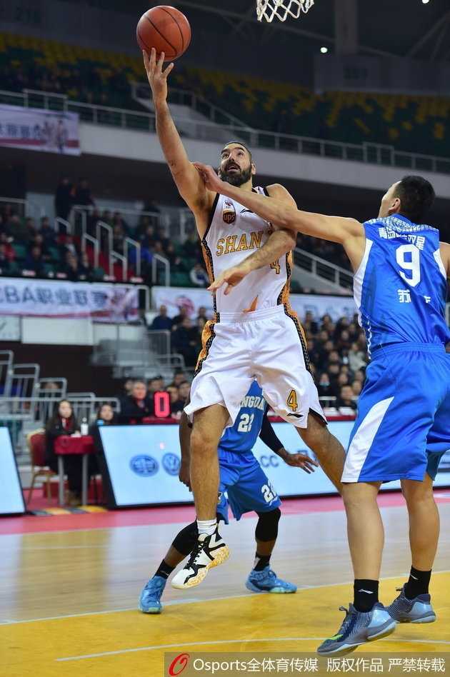 CBA焦点战:山西汾酒主场击退青岛,斯科拉吉布森上演飙分大战 山西队外援斯科拉在青岛队内线球员的严密防守下,依然稳健地运用梦幻脚步勾手投篮,眼神中充满对胜利的渴望。