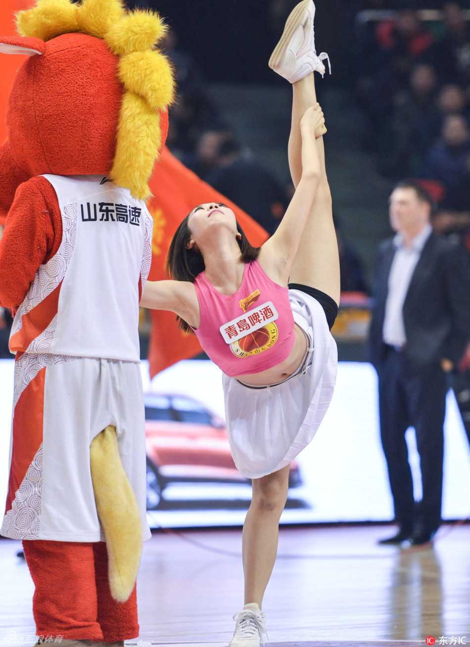 在暂停时间的场地中央，一名身着亮色表演服的队员正完成一个高难度的托举动作，周围的队友默契配合，形成一组力与美交融的雕塑群像。