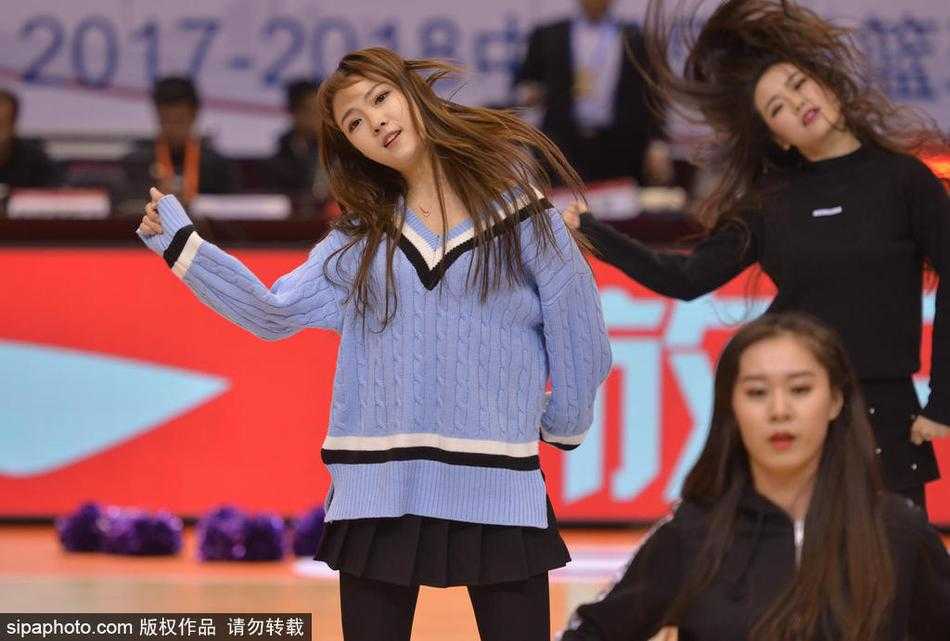 动感十足的瞬间，几名队员高高跃起，手中的金色花球在空中划出优美的弧线，她们的身体姿态轻盈而充满力量，仿佛在空旷的看台前绽放出最绚烂的烟火。