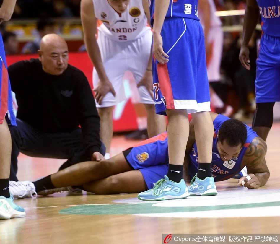 救护人员用担架将沉重的霍尔曼抬起，场边的广告牌和观众席虚化成背景，几名天津队队员默默跟在担架旁护送，目送他们的内线核心离场。