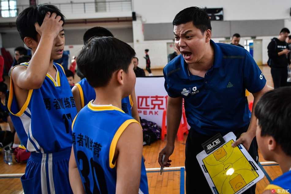 比赛进入白热化阶段，教练激动地从座位上站起来，双手拢在嘴边形成喇叭状，大声指挥着场上的攻防，面部表情因投入而显得十分丰富。