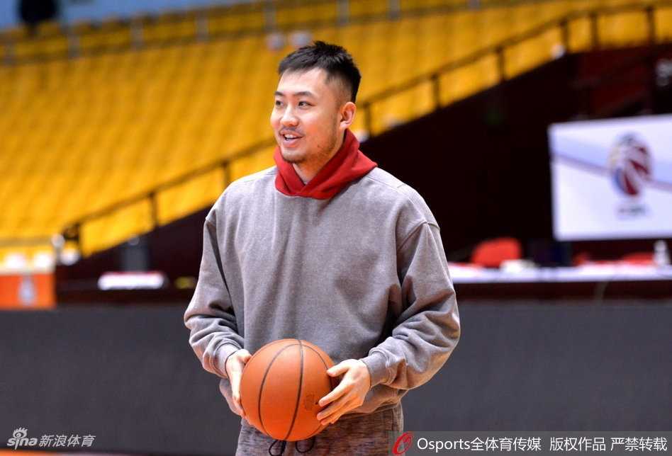 丁彦雨航在训练中露出轻松笑容，举手投足间尽显核心风范，身后的队友们也在进行着轻松的拉伸练习。