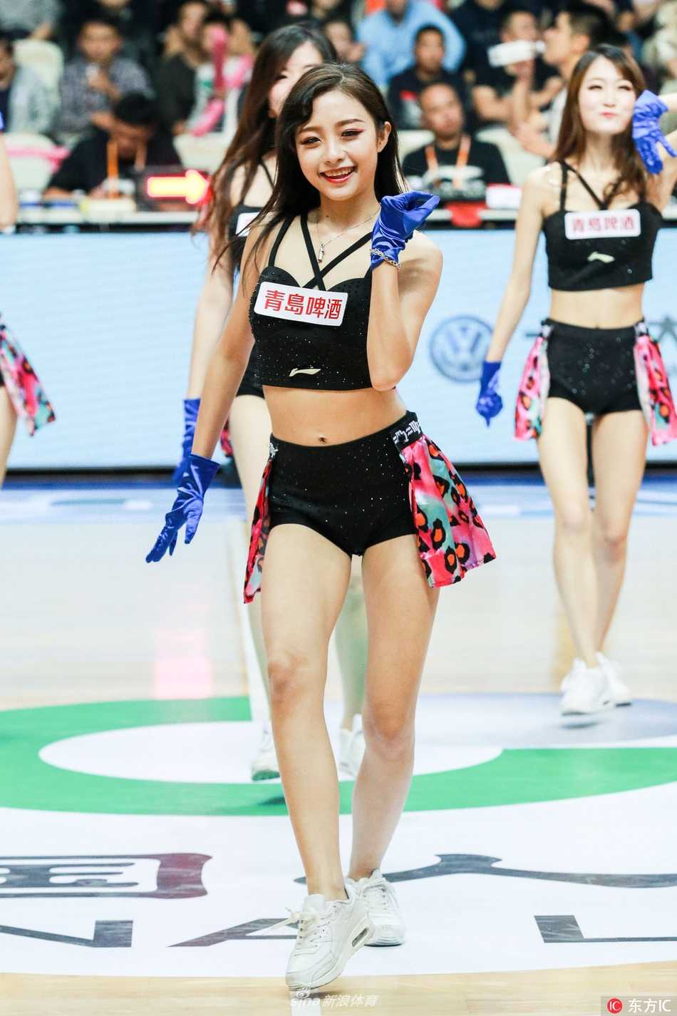 镜头拉近，这位啦啦队成员正全神贯注地完成一个俏皮的 waving 动作，她手中的花球随着身体的律动划出优美的弧线。背后巨大的上海哔哩哔哩队 LOGO 与她的青春气息相得益彰，完美诠释了竞技体育与流行文化的化学反应。