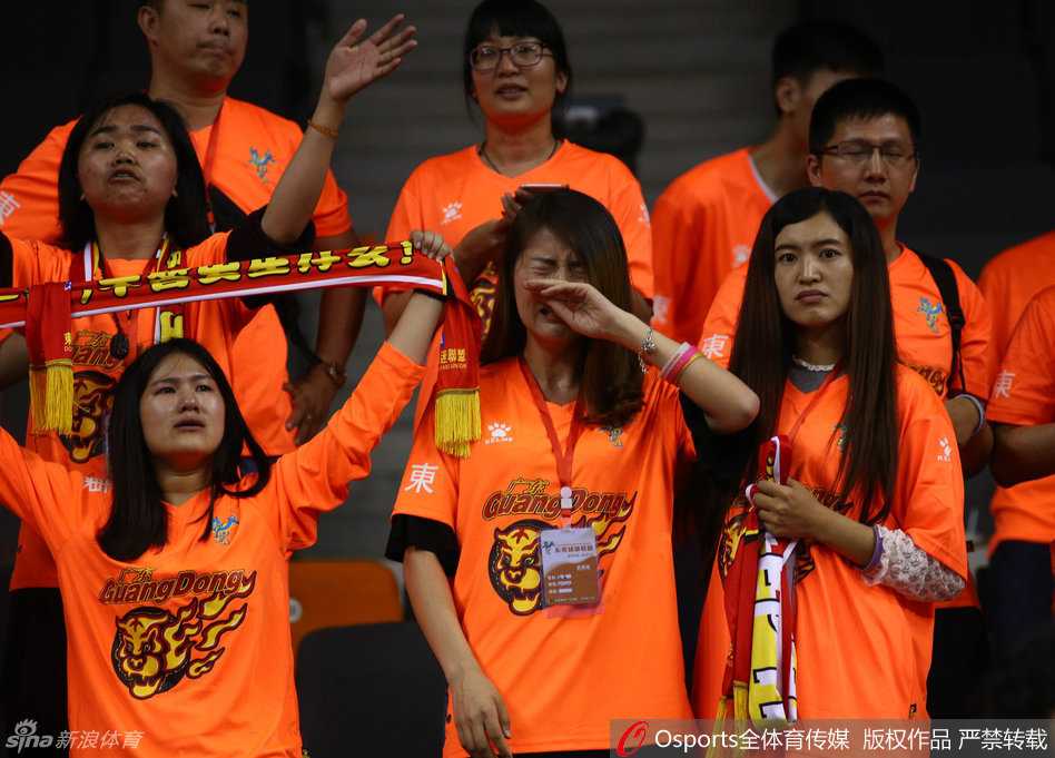 一位身穿橙色助威服的广东女球迷，在球队失利后双手掩面，泪水止不住地流淌，悲伤的情绪感染了周围的每一个人。