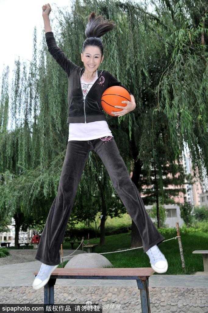 梁燕燕手举篮球轻盈跃起，纯真笑容洋溢在脸上，篮球服勾勒出修长身姿，仿佛将夏日的活力定格在空中。