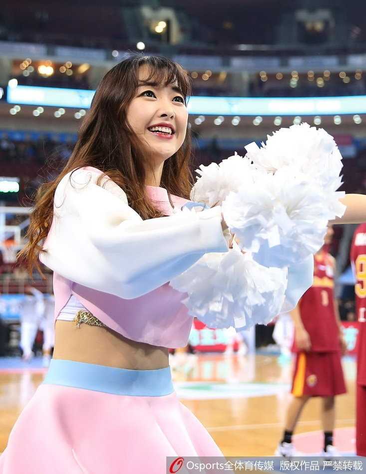 特写镜头捕捉到一位篮球宝贝的甜美笑容，她手持彩色花球，眼眸中闪烁着舞台灯光的光芒，青春的气息与赛场的热血在此刻完美交融。