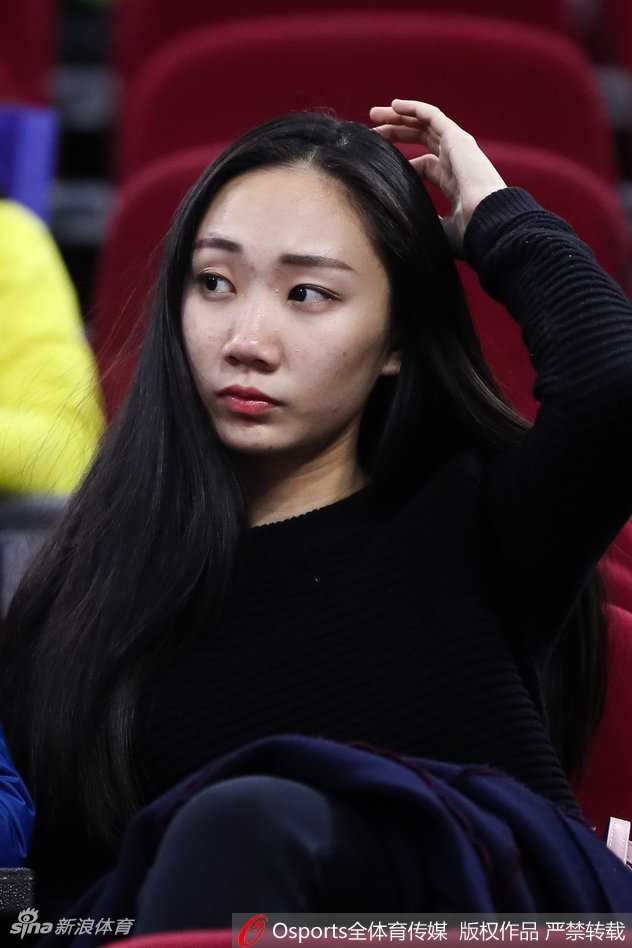 赛场边的美女球迷正用手机记录下这一刻，她身着一件宽松的连帽卫衣，显得青春俏皮。背景是模糊的看台人群，焦点中她脸上的兴奋与好奇清晰可见，仿佛要将这份主场的激情永久珍藏。