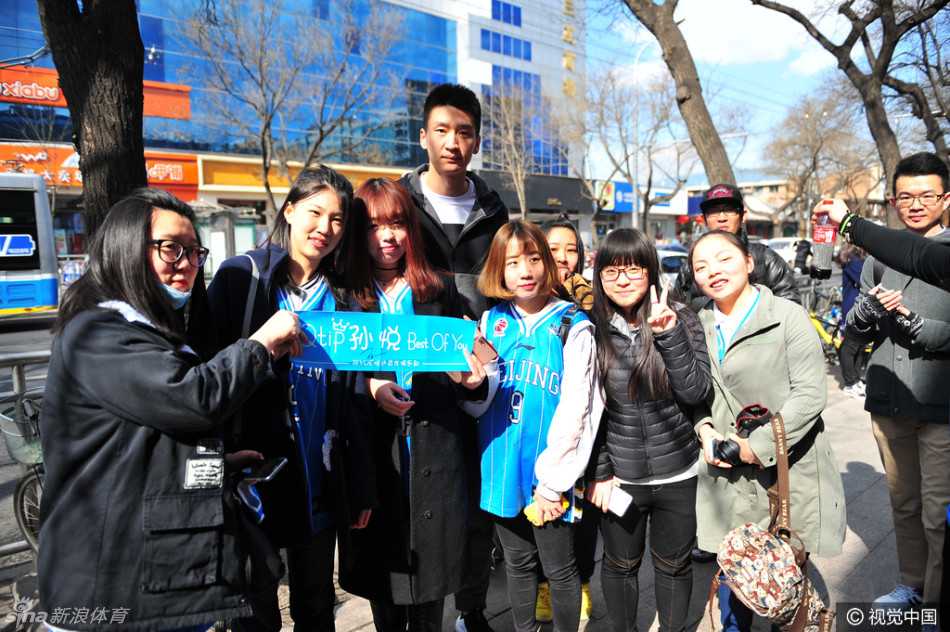 孙悦和方硕在品牌店内与热情的球迷们近距离互动，两人神情专注，正低头为球迷手中的纪念品签下名字，现场气氛高涨