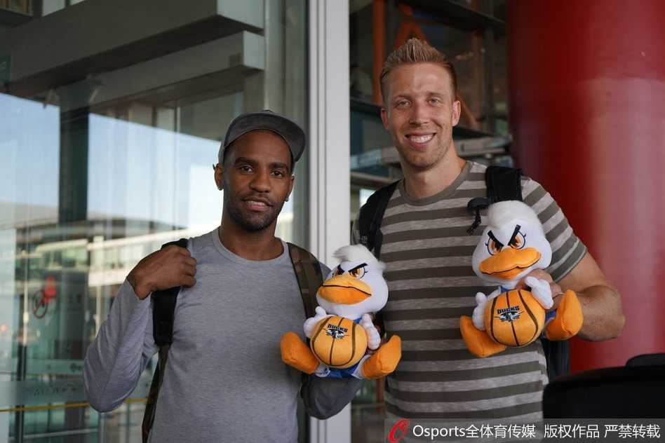 身穿休闲装的汉密尔顿推着行李车走出通道，脸上带着温和而好奇的微笑，眼神中闪烁着对这座古老而又现代城市的好奇与憧憬。