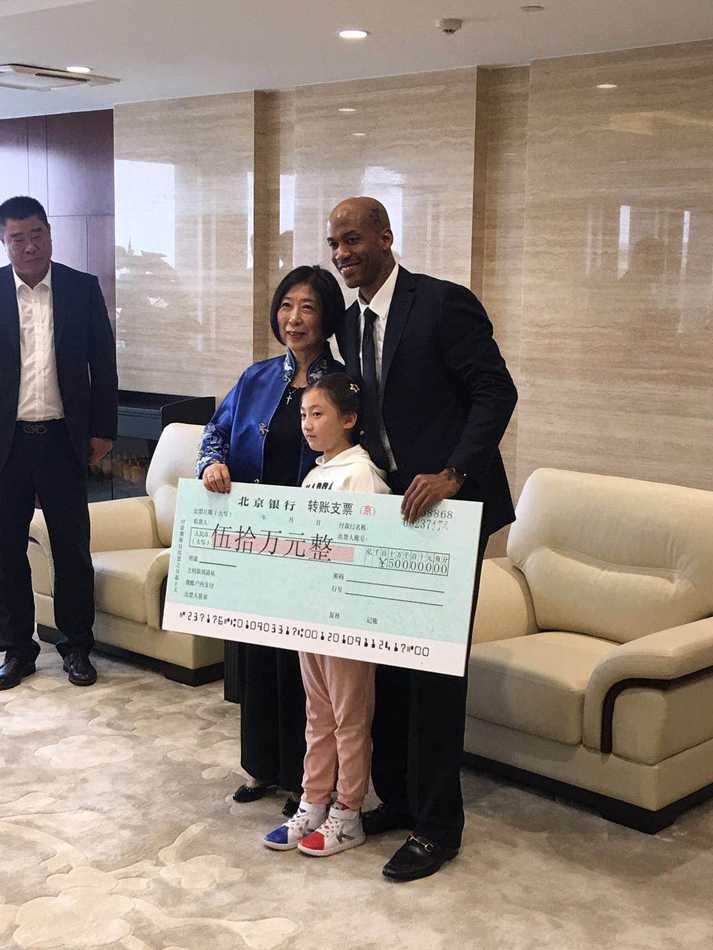 年过七旬的张阿姨面带慈祥笑容，双手郑重地将一张巨大的五十万元支票展板递到马布里面前，眼神中满是对偶像的关爱与支持。