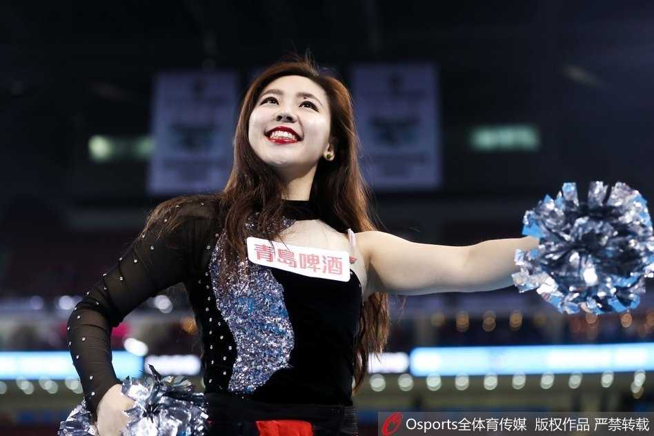 在这张俯拍镜头中，篮球宝贝们排成整齐的队列，她们手中挥舞着闪耀的啦啦队花球，如同夜空中绽放的绚丽烟火，将球馆的氛围装点得格外热烈。