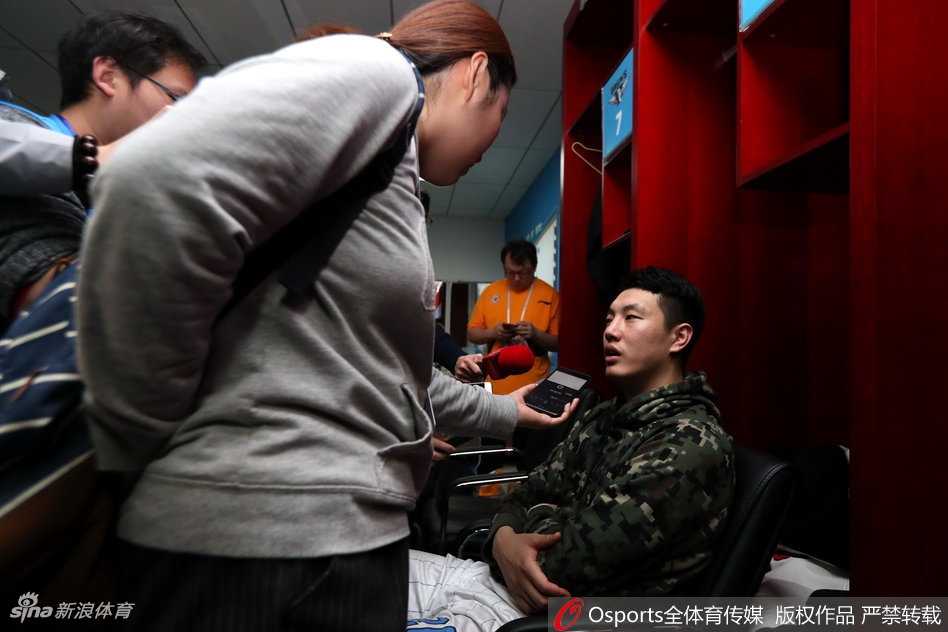 更衣柜上挂着杂乱的毛巾和装备，背景是队员们庆祝的身影，虚化的画面里仿佛能听到欢笑声，这就是一个战斗集体的温暖与力量。