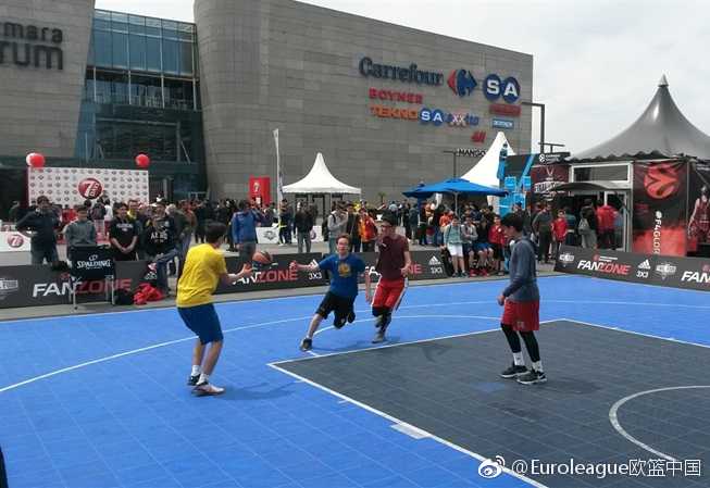 伊斯坦布尔四强赛的蓝色狂欢:马尔马拉球迷专区全记录 一群少年在球迷专区的迷你篮球场上腾空跃起,橘色皮球在空中划过弧线,背景是巨大的欧冠联赛标志,青春的活力和梦想在此刻定格。