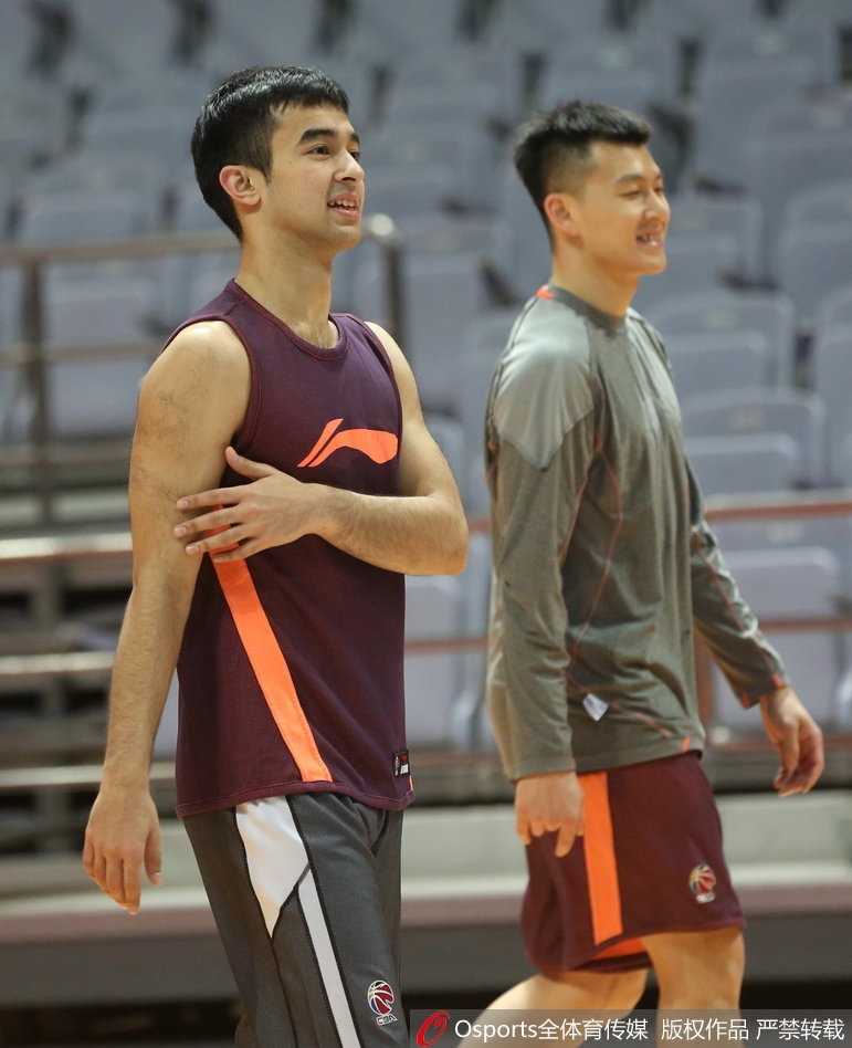 王治郅与恩师尤纳斯在赛前训练场边相遇，两人紧握双手，大郅面带谦逊微笑，尤纳斯则眼神关切，仿佛在进行一场无声的战术交流，周围队友纷纷侧目，画面充满温情与敬意。