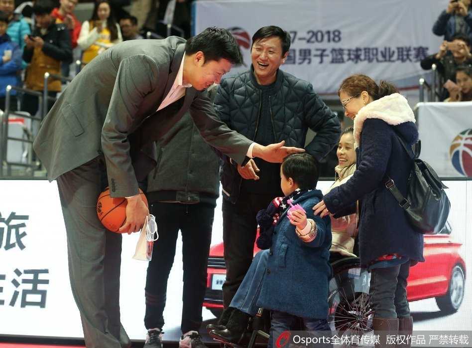 桑兰坐在轮椅上，脸上洋溢着灿烂的笑容，她身边的儿子好奇地望着球场方向，母子俩正在等待一场篮球盛宴的开始。