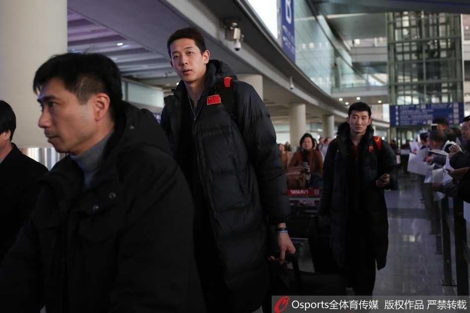 从另一个角度看去，李楠和王哲林在等待行李的间隙交流甚欢，李指导用手比划着，似乎在与大王复盘比赛中的某个精彩瞬间。