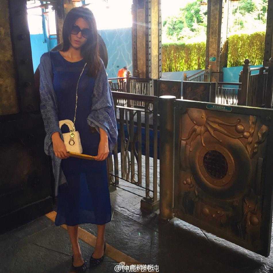 钟鹿纯身穿绿色休闲外套，坐在室内享受着悠闲时光，五官立体精致，眼神清澈明亮，宛如画中走出的优雅女神。