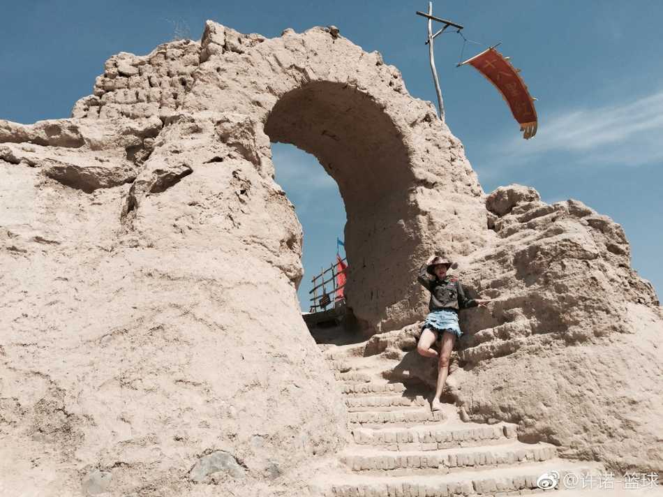 许诺站在充满西部风情的荒漠中，双手插兜，一件简单的白T恤搭配短裤，将她那双笔直修长的美腿衬托得淋漓尽致，笑容灿烂又自信。