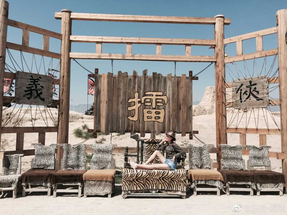 夕阳的余晖洒在许诺身上，她身穿简约的白色上衣，依靠在古朴的土墙边，脸上带着温婉的笑容。光影勾勒出她修长的身形，让这双大长腿显得格外温柔而有故事感。