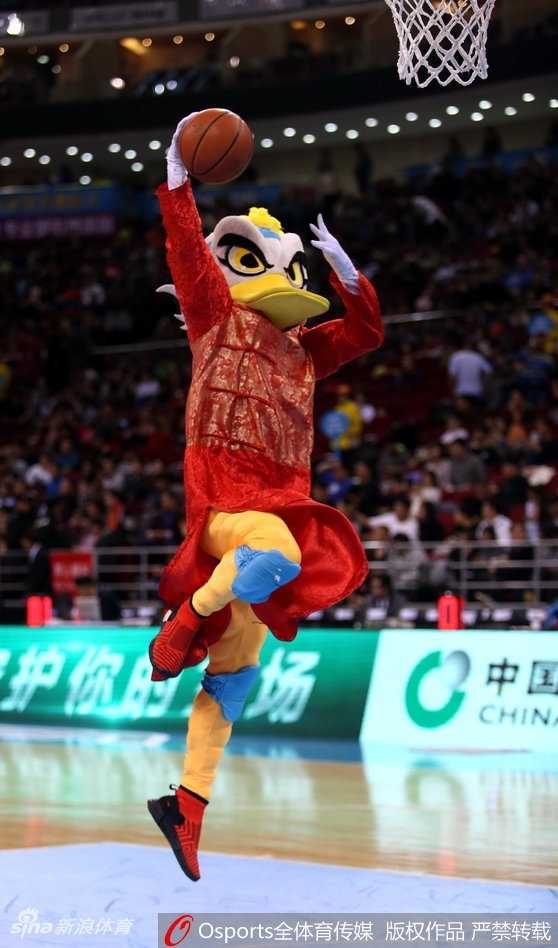 北京篮球圣地春节红 霹雳鸭盛装助力首钢挺进季后赛 霹雳鸭身着红色唐装,正弯下腰与场边一位同样穿着红色棉袄的小朋友击掌互动,小朋友脸上洋溢着惊喜的笑容。