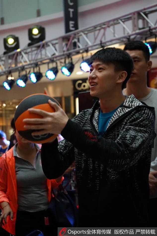 翟晓川在展板前签名留影，神情专注而放松，身后队友的目光汇聚一处，构成一幅团结一心的画面