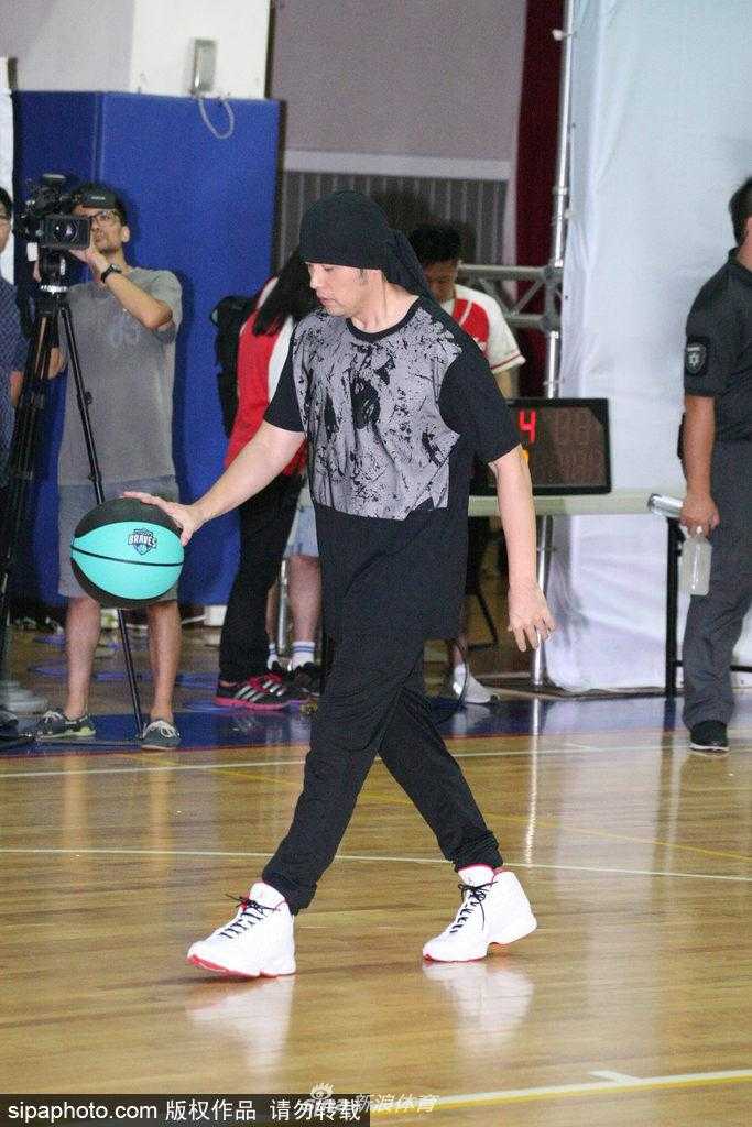 周杰伦裹头巾英姿飒爽现身球场 携富邦勇士为偏乡学童点燃篮球梦 周杰伦在场上指挥跑位,他伸出手臂指向篮筐方向,头巾的结打在脑后,侧脸线条分明,神情专注而认真,完全沉浸在比赛的乐趣中。