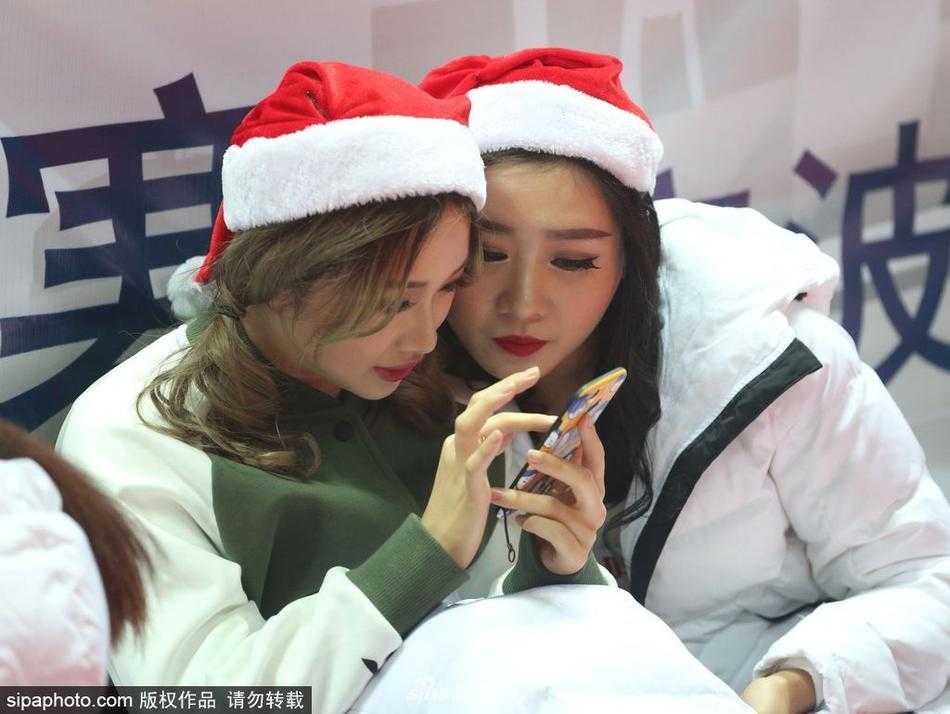 圣诞夜的雅戈尔体育馆:八一男篮背后的篮球宝贝与她们的场下瞬间 比赛间隙,两位篮球宝贝凑在一起看着手机屏幕,其中一位惊讶地捂嘴,仿佛看到了什么有趣的内容,可爱的表情与场上严肃的拼抢形成鲜明对比。