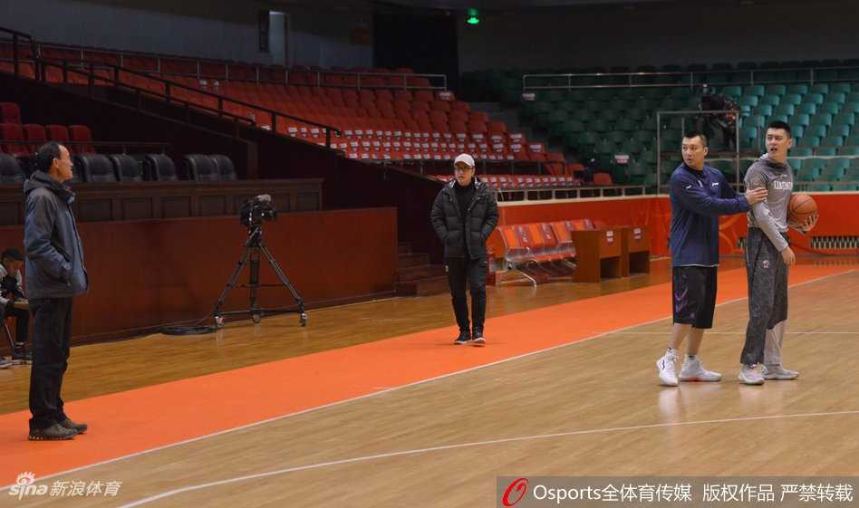 辽宁队助理教练紧紧抱住试图上前理论的杨鸣，杨鸣身体前倾，眼神中充满不甘，背后是空旷的山东主场看台。