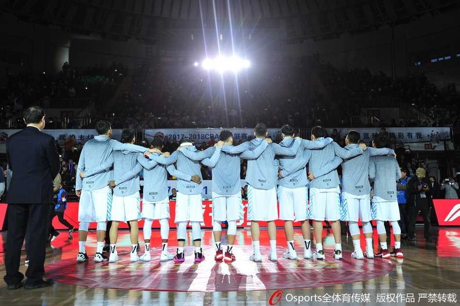 新疆队全体成员在场地中央围成一圈，共同将手中的总冠军戒指朝向镜头，每个人的脸上都绽放出最灿烂的笑容，记录下这支冠军之师最完整、最荣耀的大家庭合影。