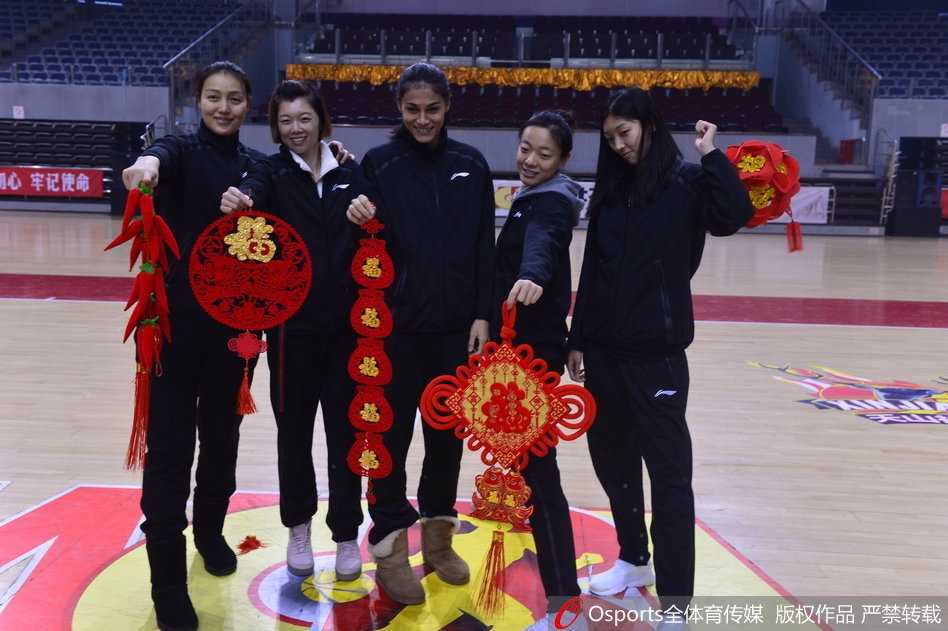 王丽丽手持春联，笑容灿烂，身后的队友们凑在一起看向镜头，这幅画面象征着传承与团结，也预示着新的一年球队将焕发新生。