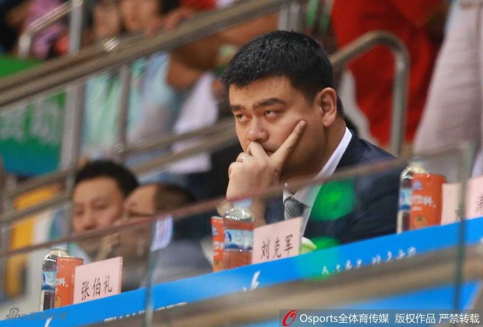 篮协主席姚明神情专注地坐在看台上，双手习惯性地托腮，目光深邃地凝视着赛场，仿佛在审视中国篮球未来的无限可能。