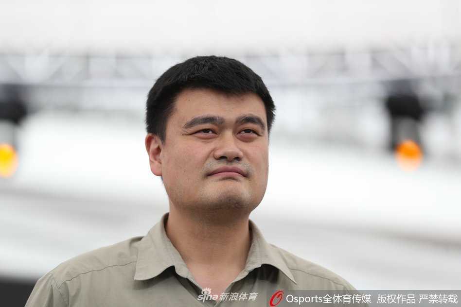 姚明在开幕式致辞中面露微笑，眼神中透露出对三人篮球未来的憧憬与坚定，背景是色彩斑斓的赛事主视觉，象征着青春与活力。