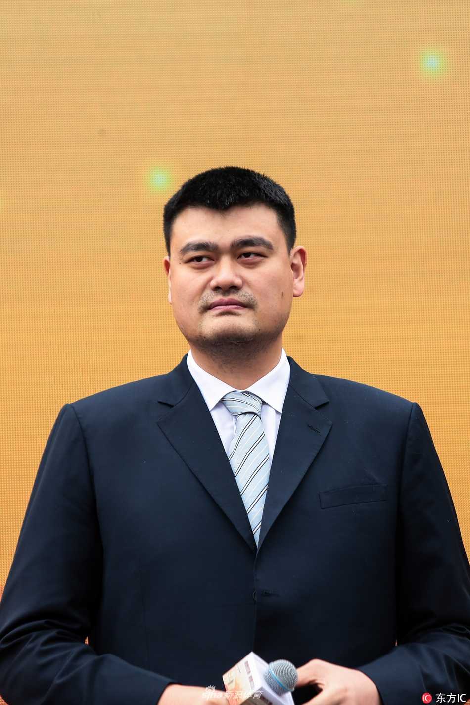 教室讲台旁，姚明正与一名男生进行情景互动，他微微弯腰，眼神专注地看着面前表情投入的男生，似乎正在模拟如何拒绝朋友递来的酒杯。