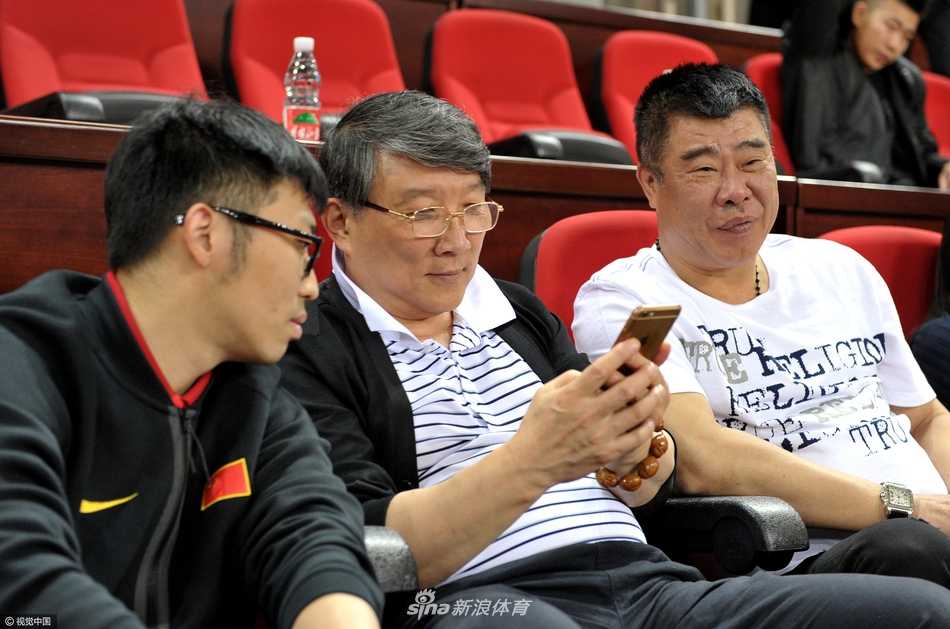 场边的宫鲁鸣低头查看手机，神情专注。即便是在观赛放松时刻，他依然保持着与外界的紧密联系，或许正在关注着中国篮球的点点滴滴。
