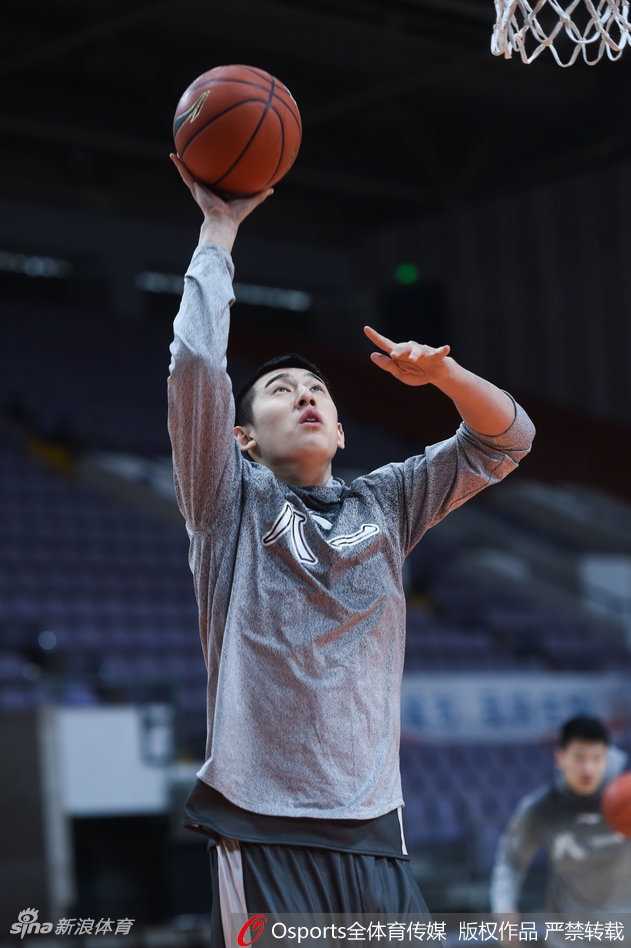 丁伟指导侧身靠近阿的江，手指向场内，似乎在分享一个重要的战术观察，两人身后的球员正在紧张热身。